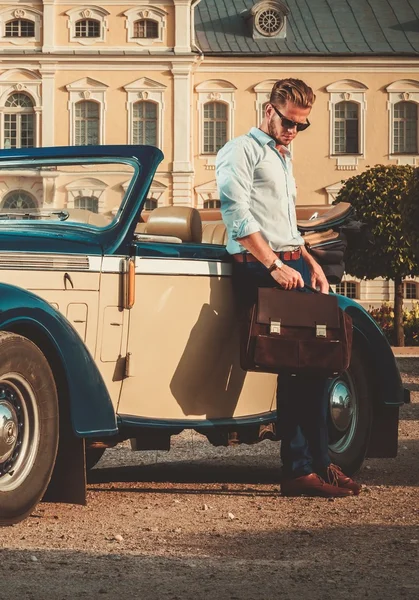 Человек с портфелем рядом с классическим кабриолетом — стоковое фото