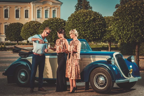 Friends drinking champagne near classic convertible — Stock Photo, Image