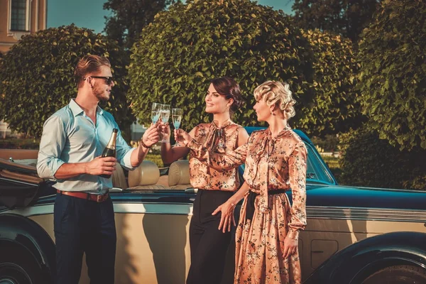 Amigos beber champán cerca de convertible clásico —  Fotos de Stock