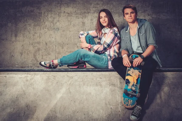 Mladý pár s skateboardu a kolečkových bruslích venku — Stock fotografie