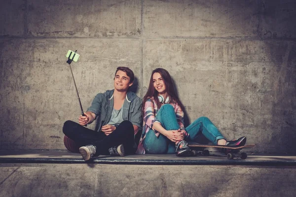 Pareja joven con monopatín tomando selfie al aire libre —  Fotos de Stock