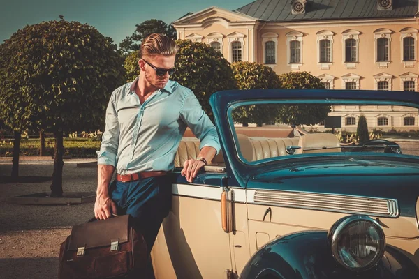 Человек с портфелем рядом с классическим кабриолетом — стоковое фото