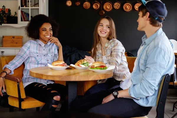 Alegre amigos multirraciais comendo em um café — Fotografia de Stock