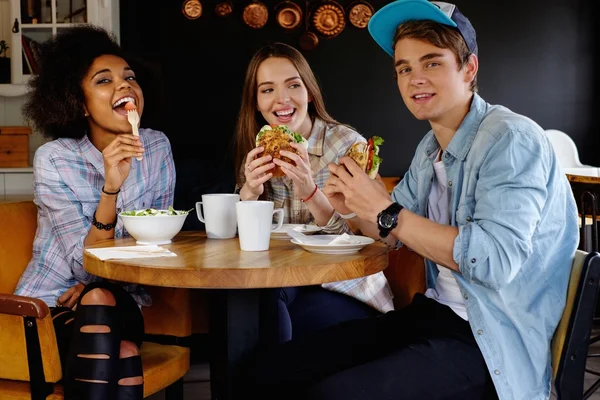 Alegres amigos multirraciales comiendo en un café —  Fotos de Stock