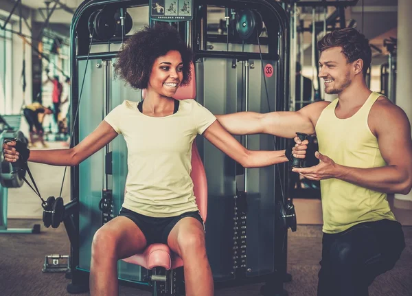 Entrenador explicando cómo utilizar la máquina de entrenamiento en un gimnasio — Foto de Stock