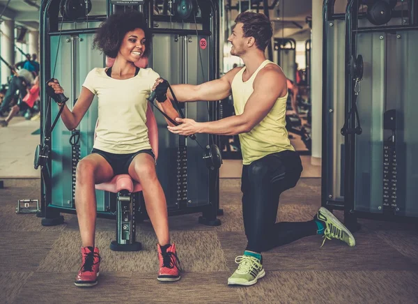 Trener wyjaœniaj¹cy jak wobec używać maszyny treningu w siłowni — Zdjęcie stockowe