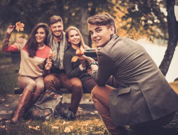 Amigos alegres en el parque de otoño tomando fotos —  Fotos de Stock