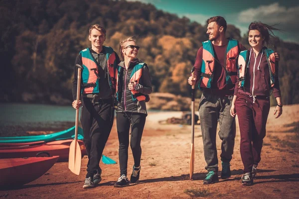 Gruppo di persone che indossano giubbotti di salvataggio vicino a kayak su una spiaggia — Foto Stock
