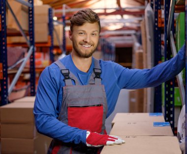 Porter carrying boxes in a warehouse  clipart