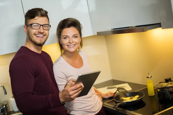 Jonge familie lezing recept op tablet in een keuken — Stockfoto