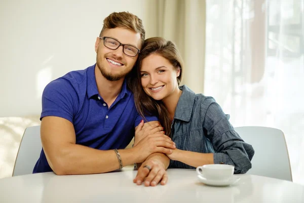 Pareja alegre detrás de la mesa en casa —  Fotos de Stock