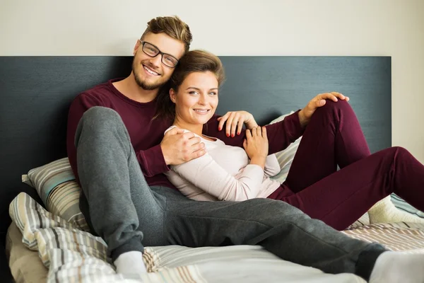 Glada par på en säng hemma — Stockfoto