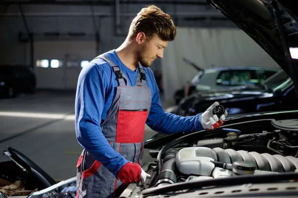 Mechaniker mit Ölfüllkorken bei offener Motorhaube in Werkstatt — Stockfoto