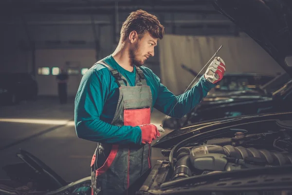 Mechanic checking oil level in a car workshop — Stock Photo, Image