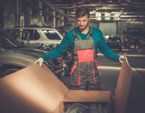 Mechaniker öffnen Box mit neuen Ersatzteilen in der Werkstatt — Stockfoto