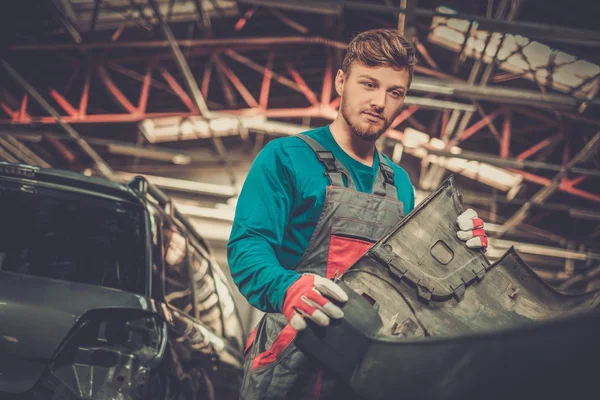 Mechanic with car bumper in a workshop — Stock Photo, Image