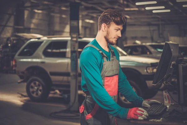 Especialista cerca de la PC de diagnóstico del coche en un taller — Foto de Stock