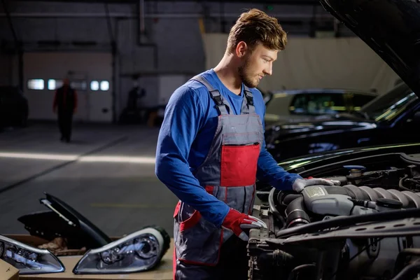 Mechaniker checkt unter Motorhaube in Werkstatt — Stockfoto