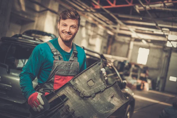 Mechanic met voorbumper auto in een workshop — Stockfoto