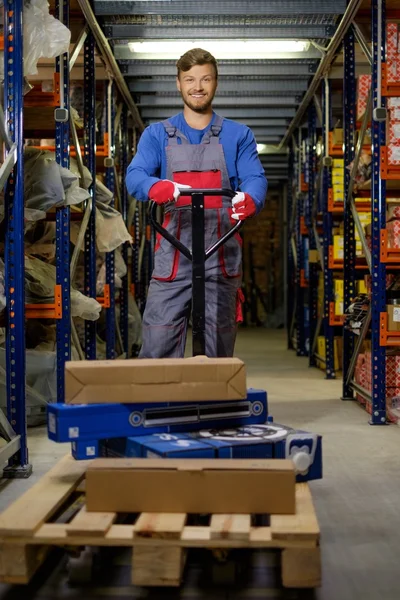 Lader met behulp van hand pallettruck in een magazijn — Stockfoto