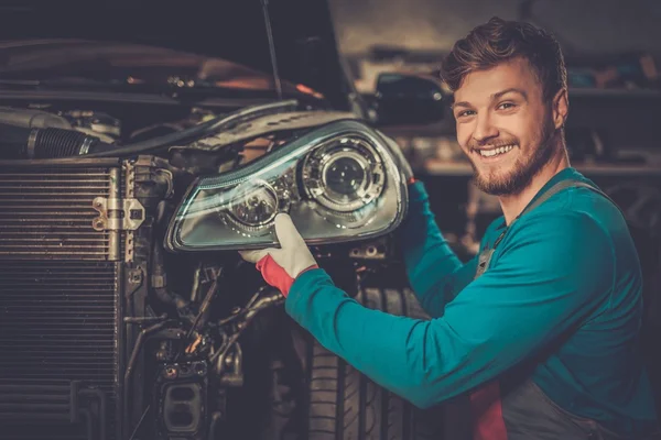 Mecánico con faro de coche nuevo en un taller — Foto de Stock