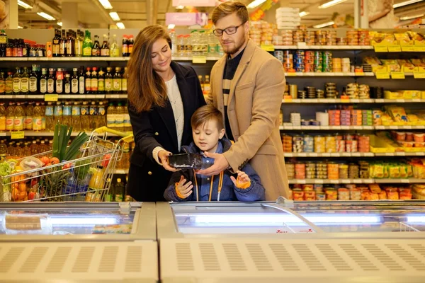 Famiglia giovane vicino al congelatore in un negozio di alimentari — Foto Stock