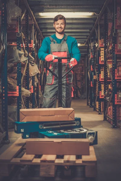 Lader met behulp van hand pallettruck in een magazijn — Stockfoto