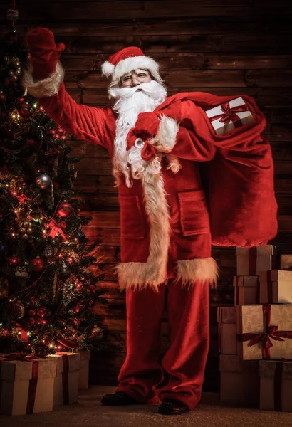 Santa Claus v dřevěných domů interiéru s pytlem — Stock fotografie