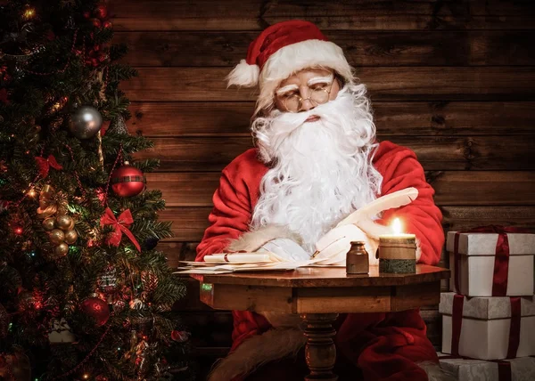 Santa Claus in houten huis interieur vergadering achter tafel — Stockfoto