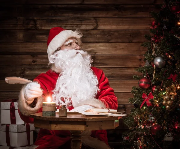 Santa Claus in houten huis interieur vergadering achter tafel — Stockfoto