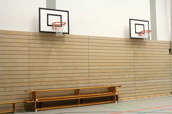 Dřevěné lavice a basketbalových košů v tělocvičně — Stock fotografie