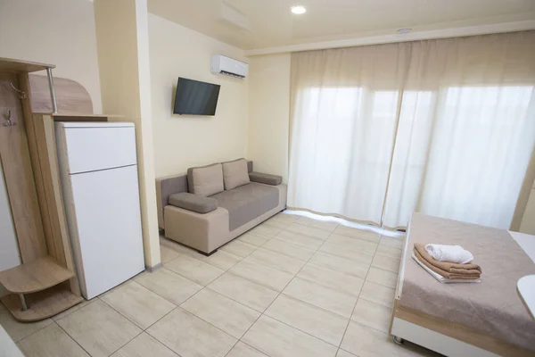 A small apartment has a hanger, a bed, a sofa for guests, a TV set, a refrigerator