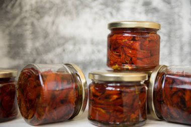 Kavanozlarda güneşte kurutulmuş domatesler izole bir şekilde masanın üzerine seriliyor..