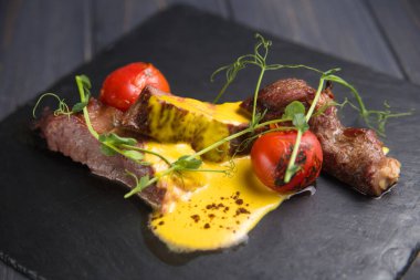 Soslu dana eti, otlarla süslenmiş bir tabağa serilmiş..