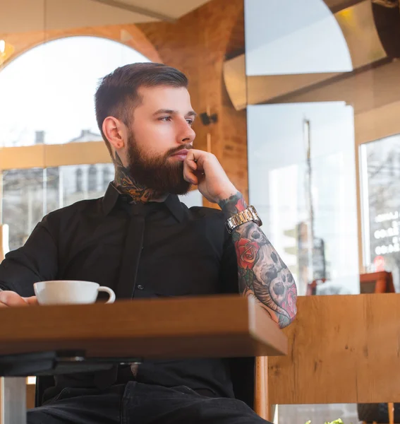 Hombre con tatuajes en un café . — Foto de Stock