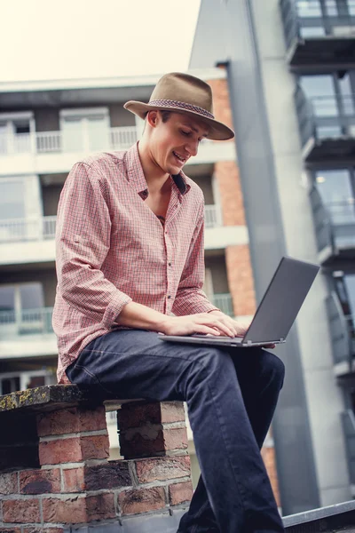 Casual man in a hat holding laptop — Stock Photo, Image