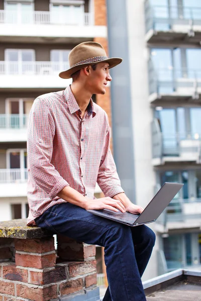 Casual homem em um chapéu segurando laptop — Fotografia de Stock