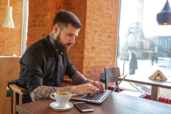 Doordachte bebaarde man met behulp van een laptop. — Stockfoto