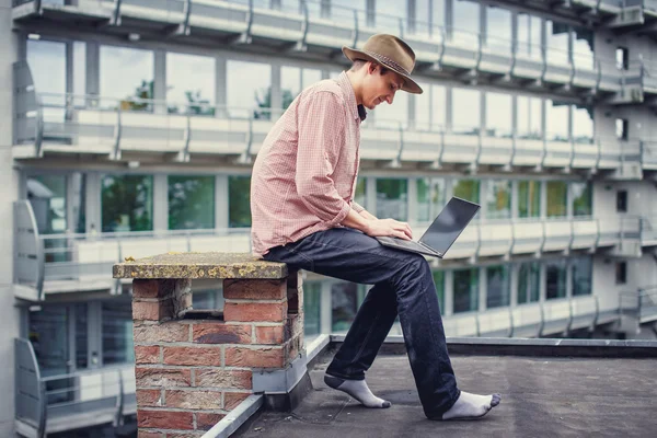 Casual homem em um chapéu segurando laptop — Fotografia de Stock