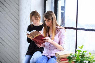 iki genç kadın kitap okuma.
