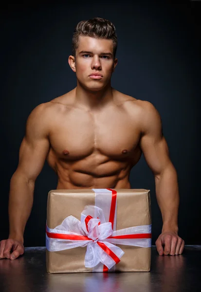 Muscular man with present box. — Stock Photo, Image