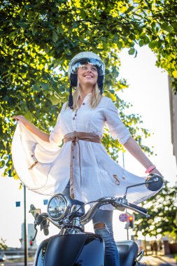 Moto scooter üzerinde gülümseyen sarışın kadın