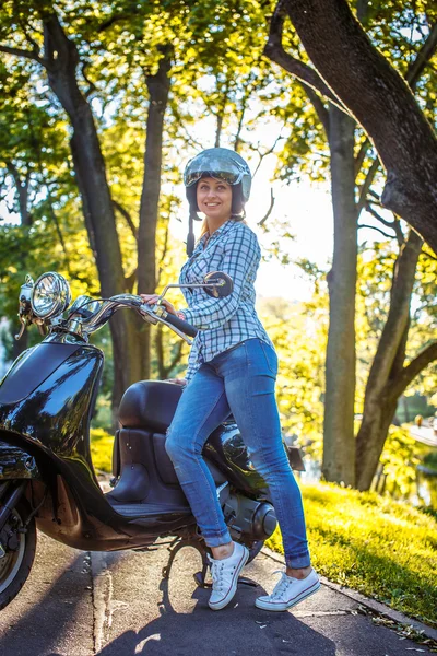 Blonde vrouw in een helm met scooter — Stockfoto