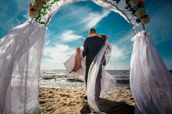 Felices recién casados en una playa — Foto de Stock