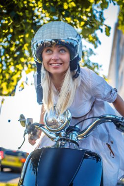 Moto scooter üzerinde gülümseyen sarışın kadın