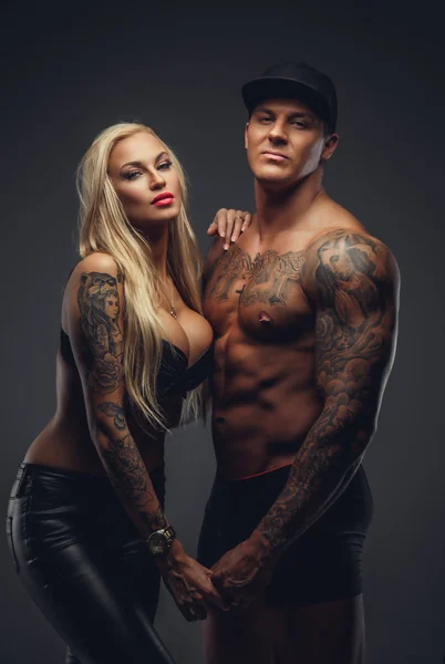 Moderno casal tatuado posando em um estúdio — Fotografia de Stock