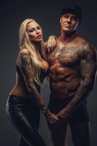Moderno casal tatuado posando em um estúdio — Fotografia de Stock