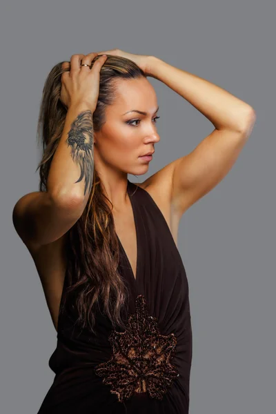 Женщина в коричневом платье с татуировкой на руке — стоковое фото