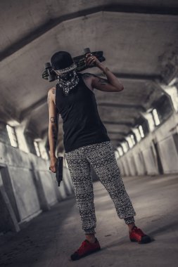 Maskeli adam silah ve kaykay tutar