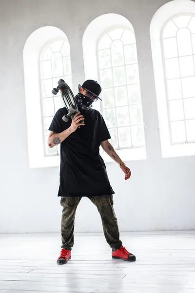 Homem em uma máscara mantém skate — Fotografia de Stock